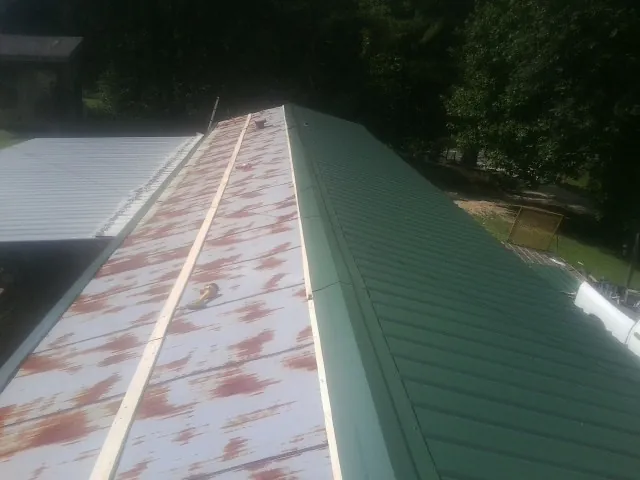 Old rusted panels beside newly installed green metal roofing — Wind Damage Roof Repair by Roofing Brothers in Santa Paula
