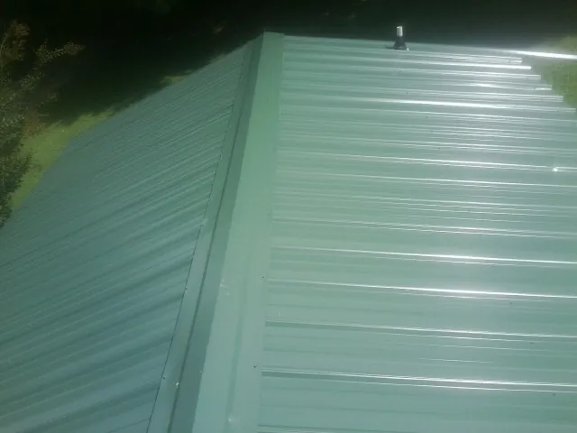 New green metal panels meeting at the ridge of a roof — Flat Roof Repair work by our crew in Santa Paula