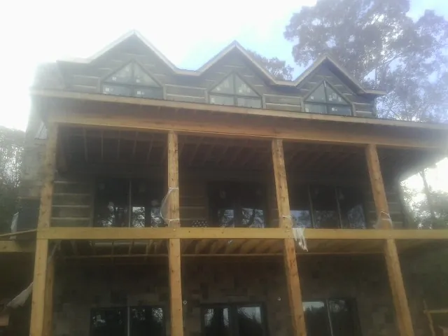 Dormers and porch framing on a large log home under construction — Roof Coating work by our crew in Santa Paula