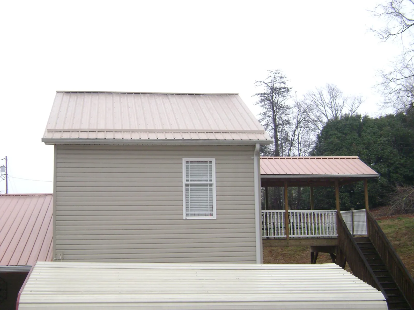 Tan metal roofs on a two story addition and attached porch, from a Roof Replacement job in Santa Paula